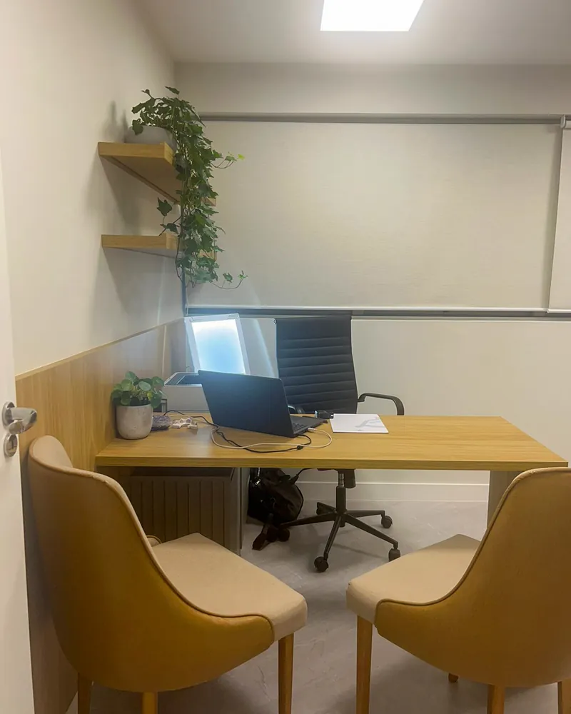 Consultório com mesa, cadeiras e prateleiras