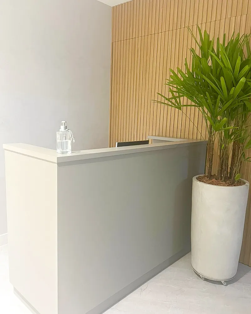 Recepção da Clínica SaluteVie, com balcão claro e painel de madeira