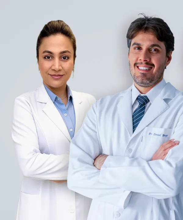Dra. Luciana Castro e Dr. Daniel Braga, de jaleco, lado a lado